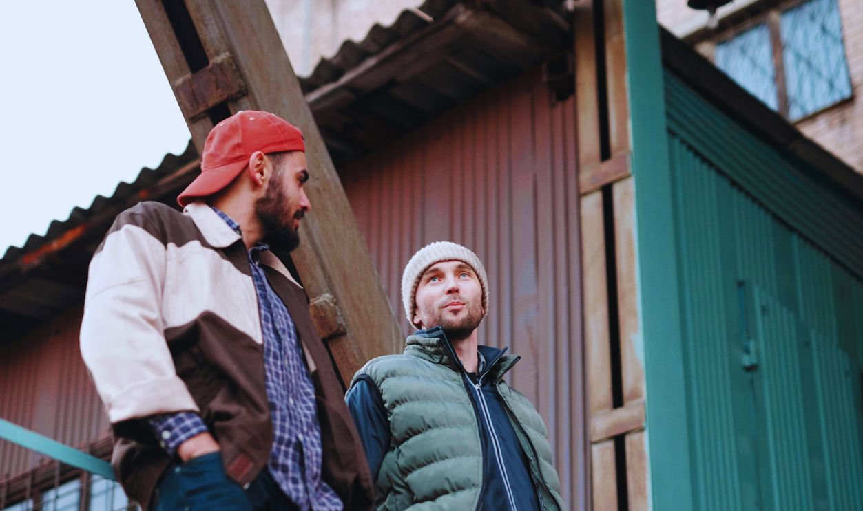 Men Leaning on Metal Railings while Having a Conversation