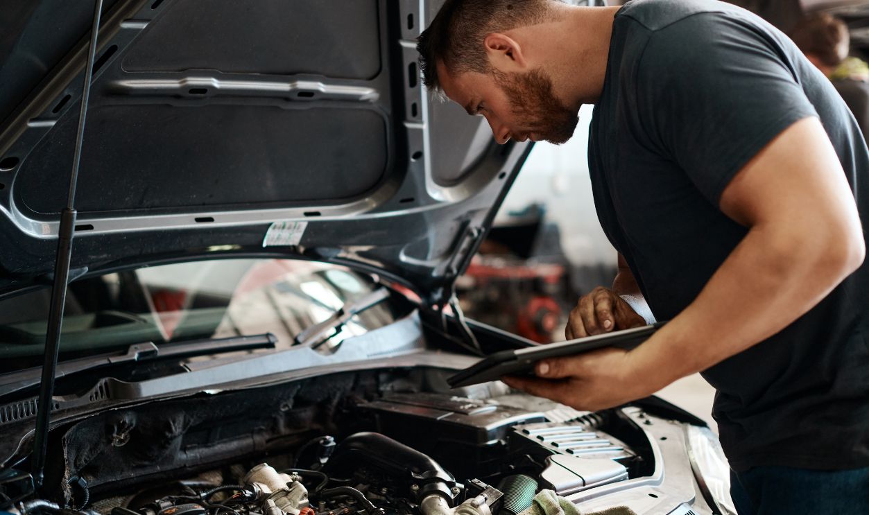 Tablet, inspection and mechanic in workshop with car service, maintenance or online auto insurance. Tech, engine and man in garage with digital app for checklist, motor repair and quality assurance