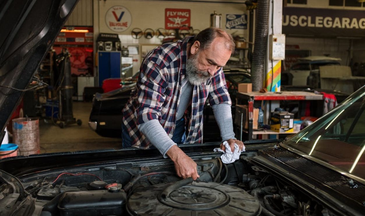 Man in Red White and Black Plaid Dress Shirt Holding Black Car
