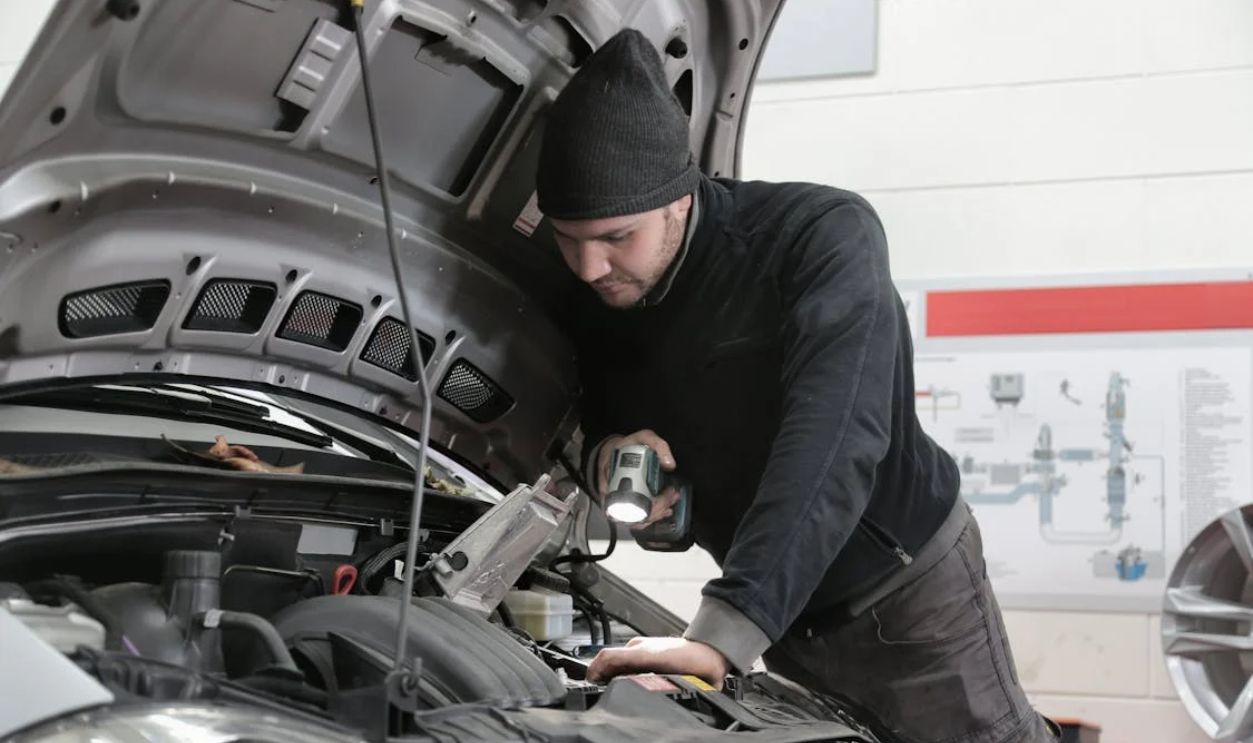 Man in Black Jacket and Black Knit Cap Inspecting Car Engine