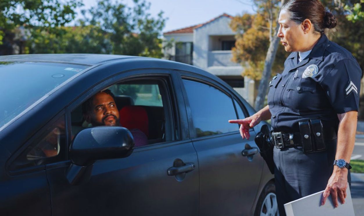Policewoman Talking to a Man Riding in a Car