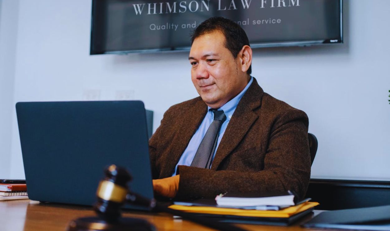 Mature Asian legislator working with laptop at table with gavel