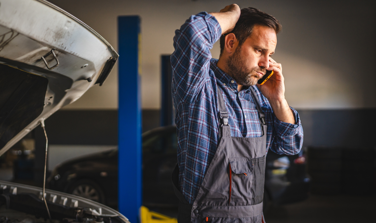 A car mechanic in a plaid shirt and overalls