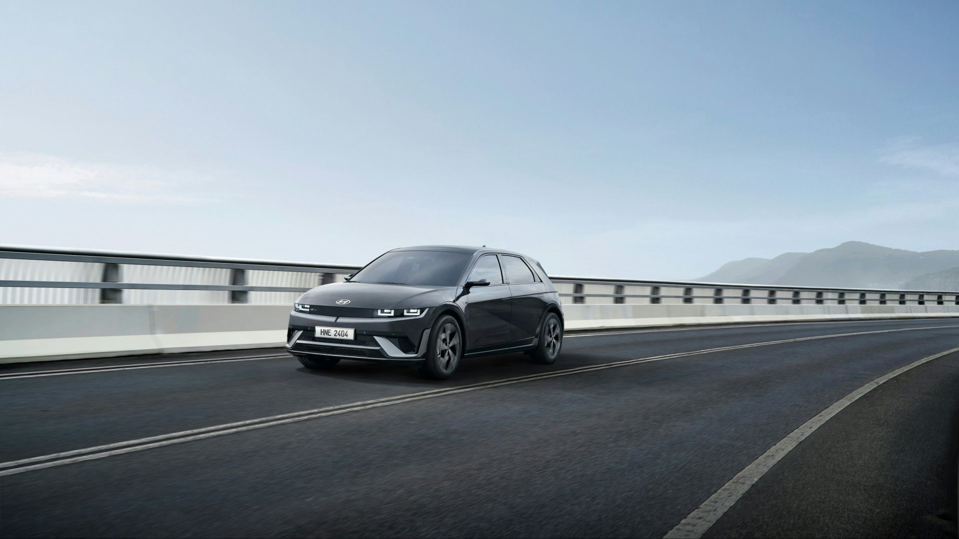 a black car driving down a highway next to a bridge