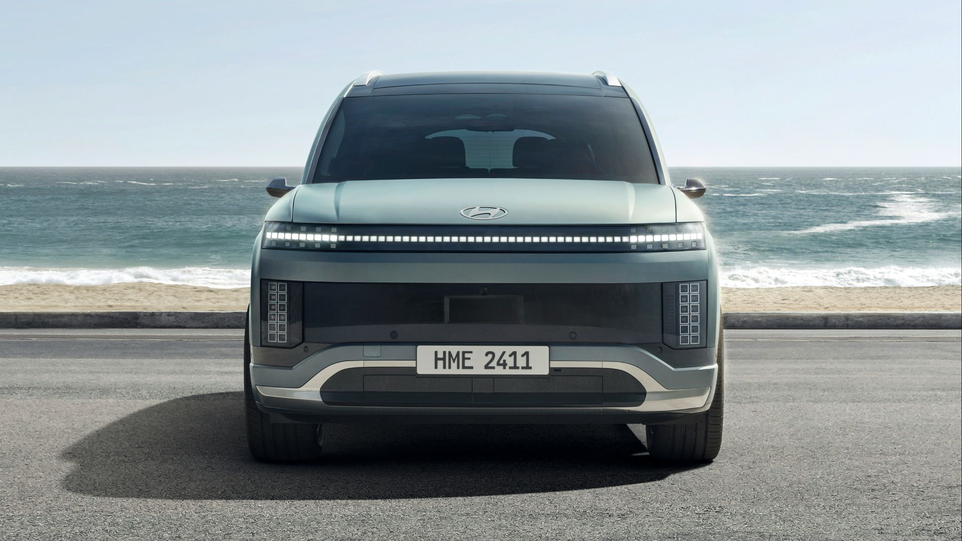 A silver car parked on the side of the road near the ocean
