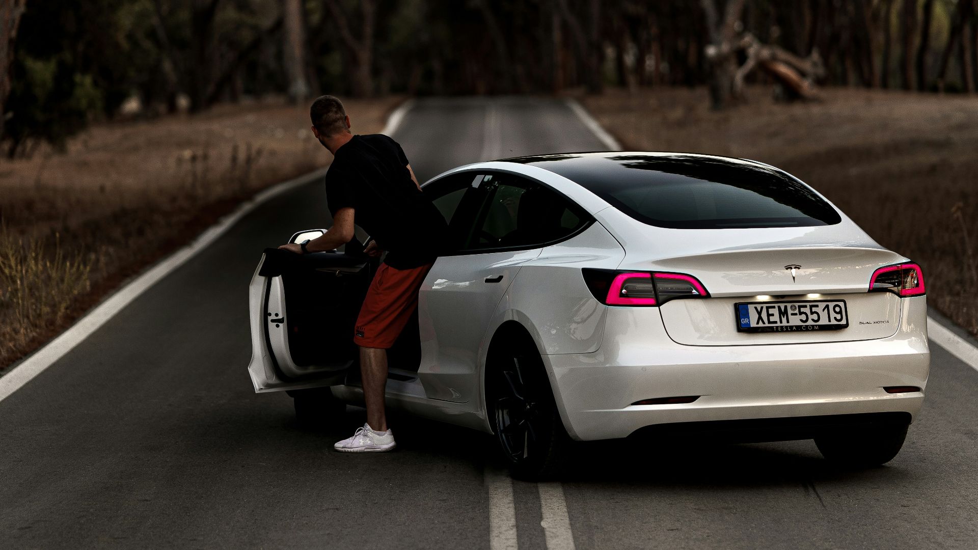 man in black t-shirt sitting on white sedan on road during daytime