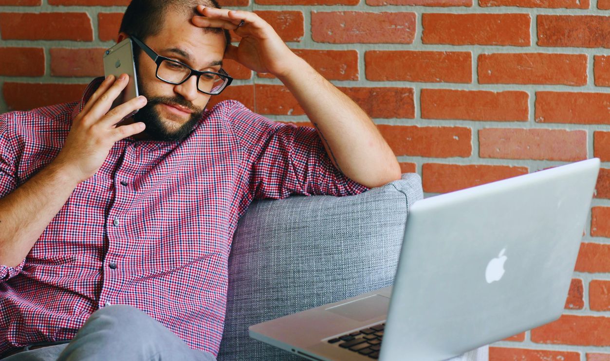 Man Sitting on Sofa While Talking on the Phone