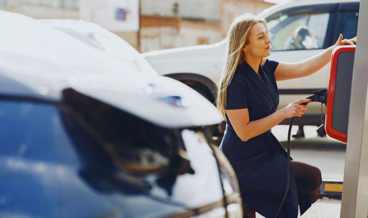 Modern woman using station for charging electromobile