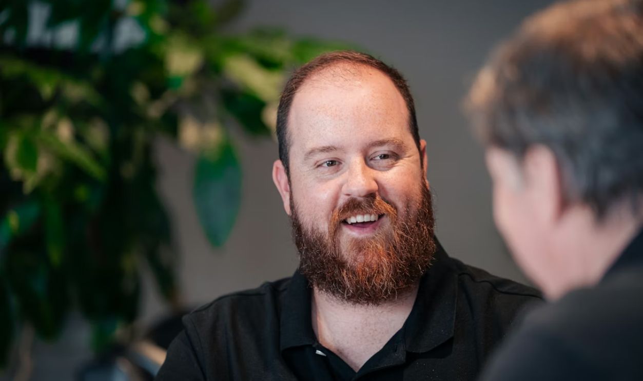 a man with a beard talking to another man