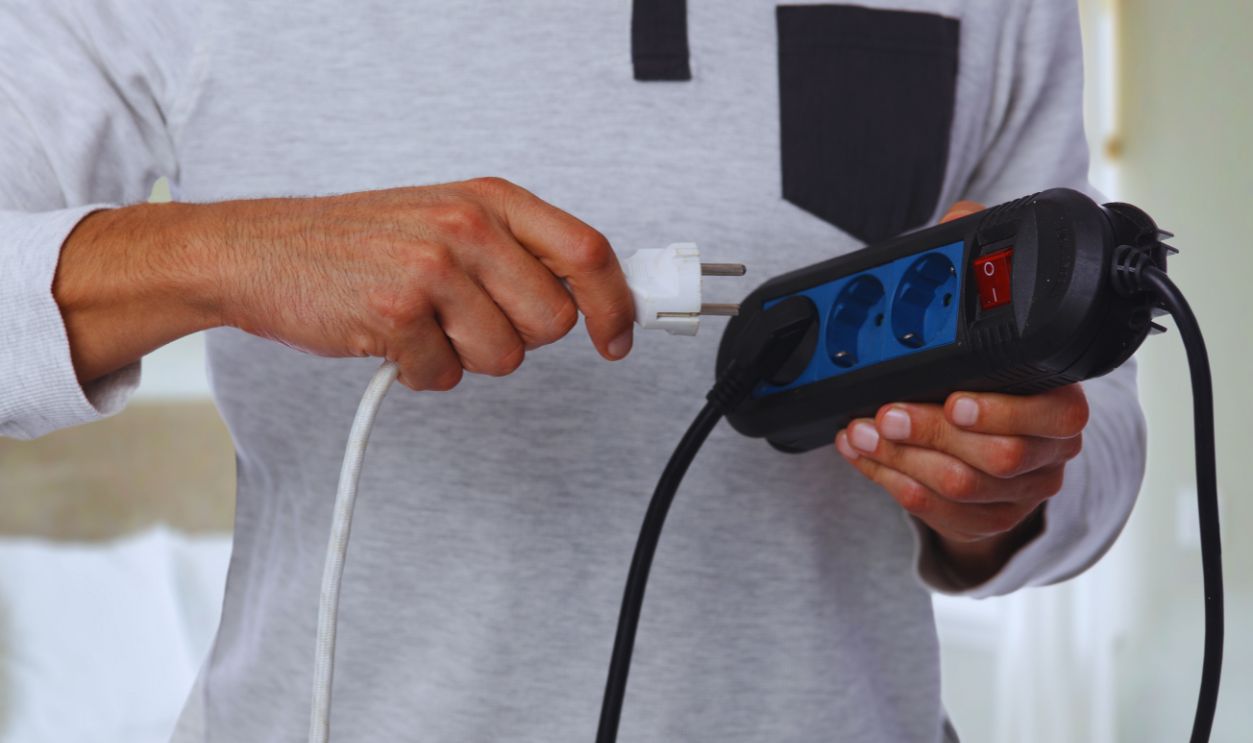  Energy saving concept. Man holding electric power extension cord.
