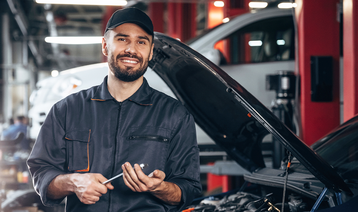 Mechanic standing in garage holding a tool