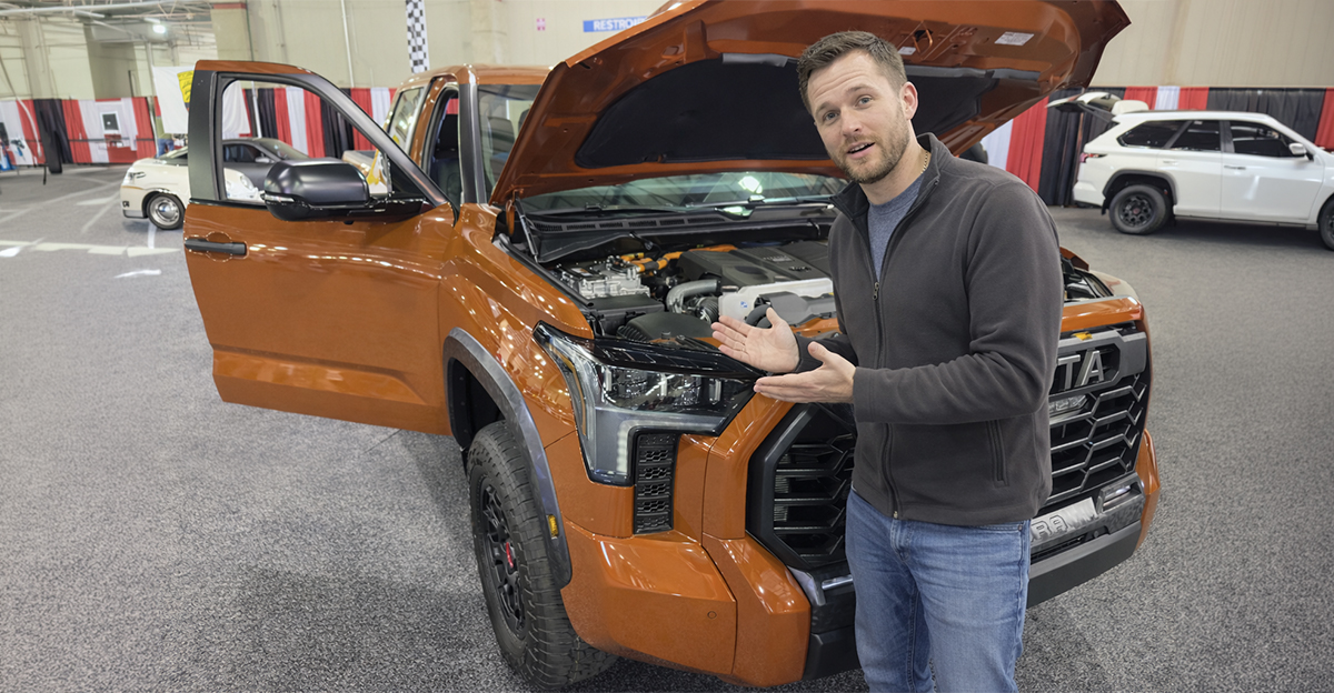 Orange 2023 Toyota Tundra full size pick up truck with open doors and hood displayed at an auto show.