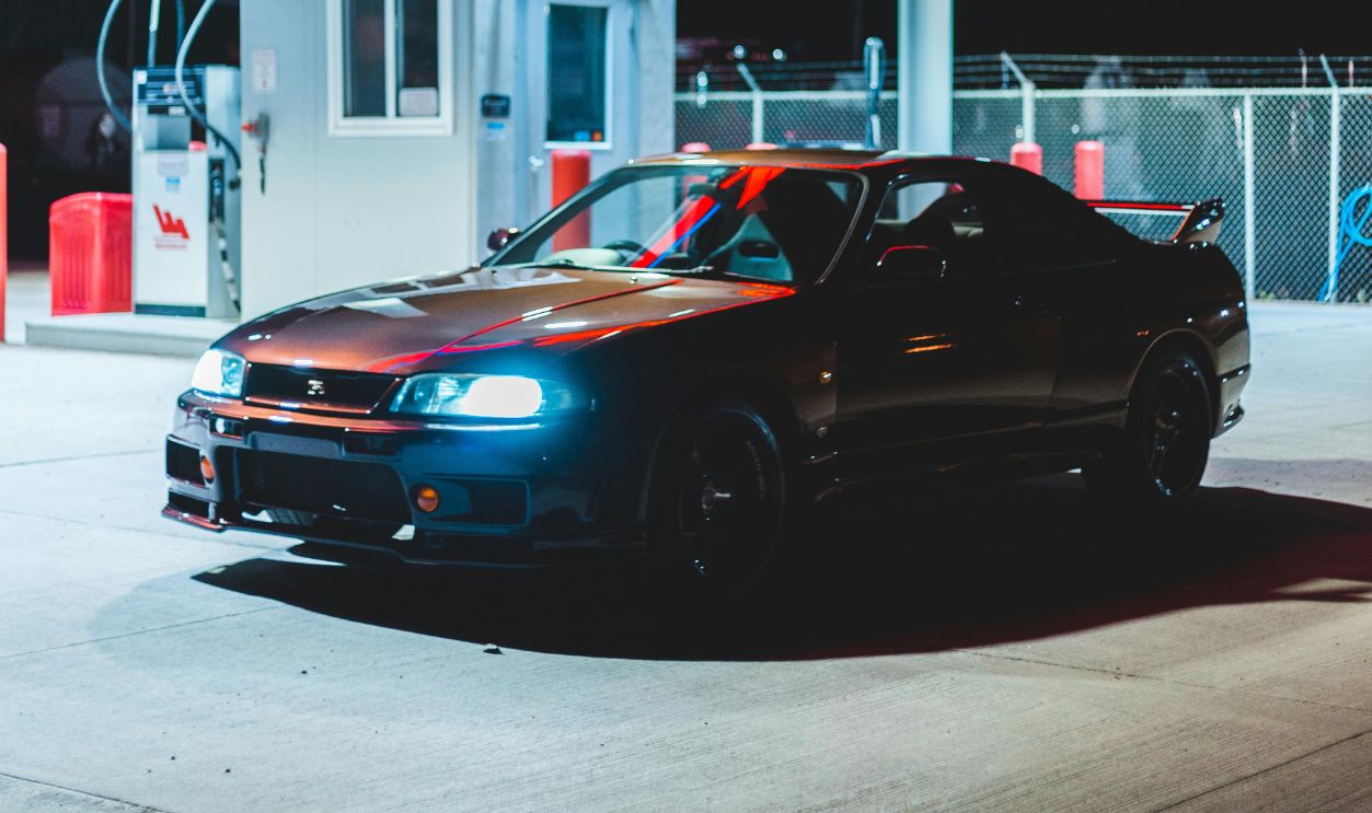 Shiny sports car in bright gas station at night