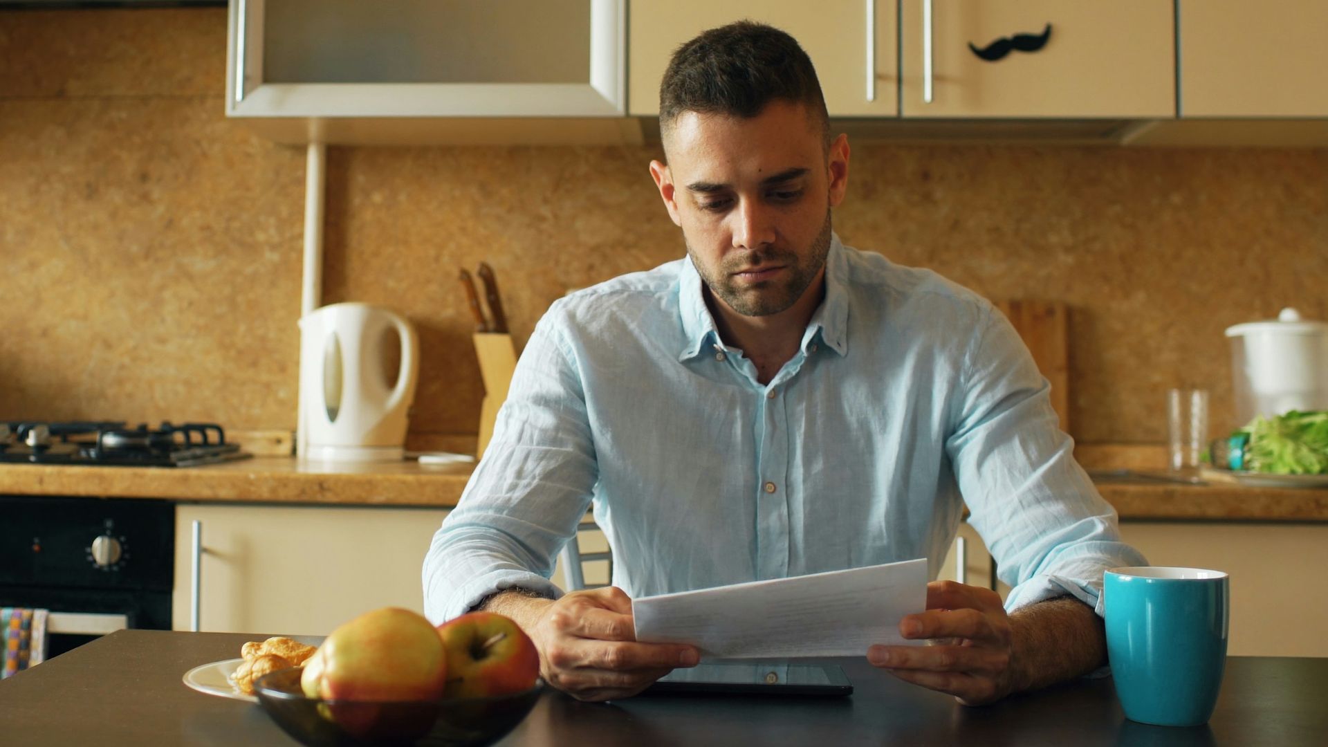 Man reading document at kitchen table with coffee