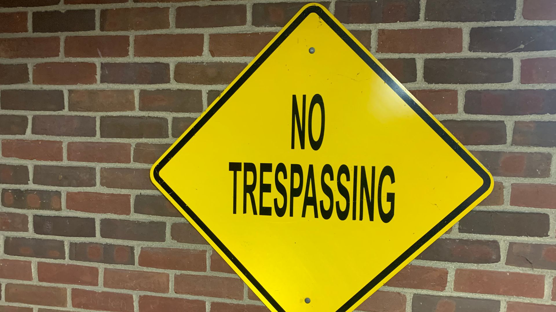 A yellow and black no trespassing sign