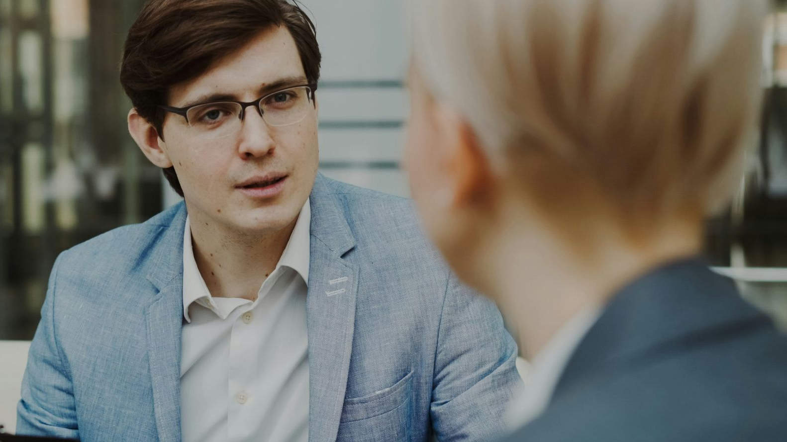 Man in suit holding clipboard talking to woman