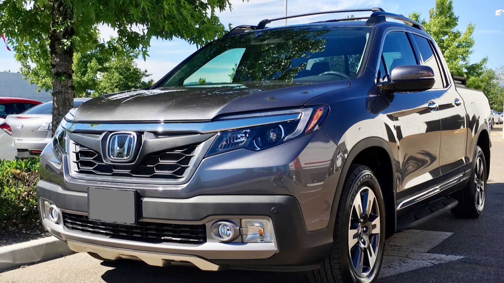 Image of a 2017 Honda Ridgeline Touring (Canadian model) with OEM accessory grille, chrome door trim, running boards, tonneau cover, roof rails and crossbars