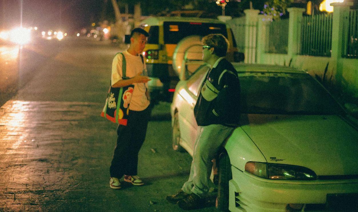 Young Men Standing next to a Car at Night and Talking