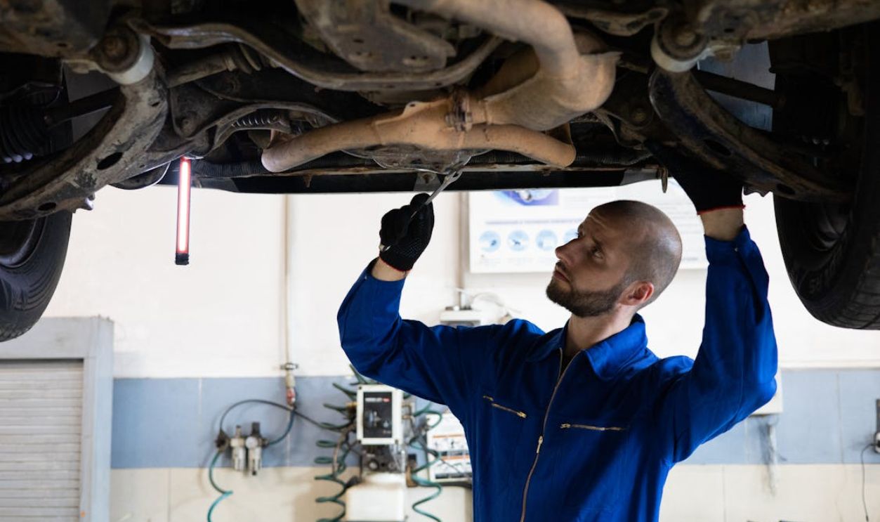Man in Blue Coverall Fixing a Vehicle