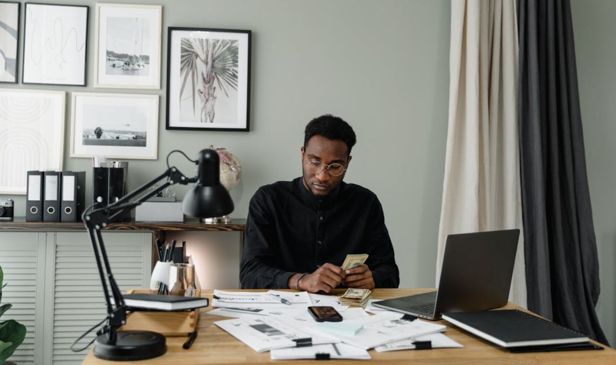 Man in Black Dress Shirt Sitting Counting Dollar Bills