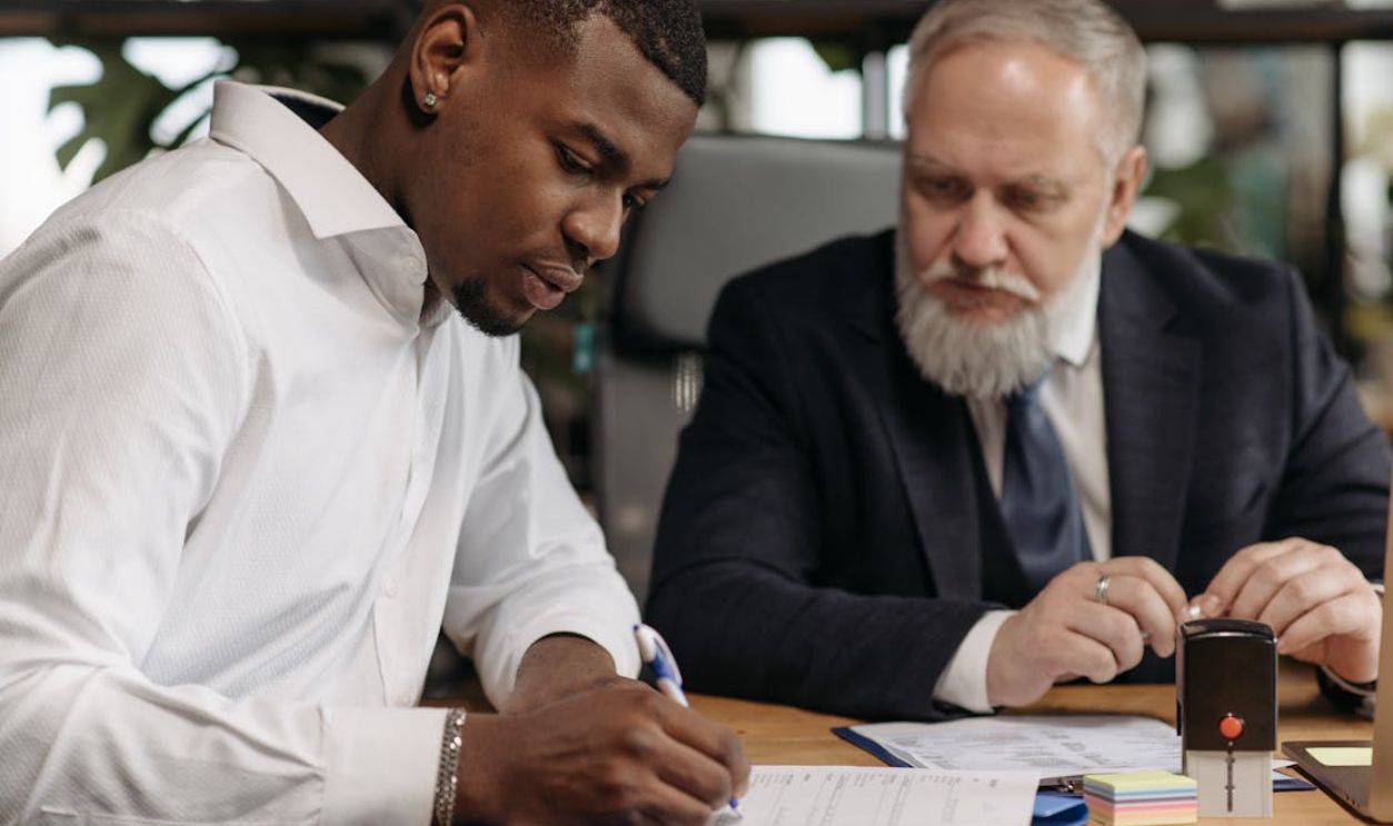A Man in Black Suit Jacket Sitting Beside Man in White Dress Shirt