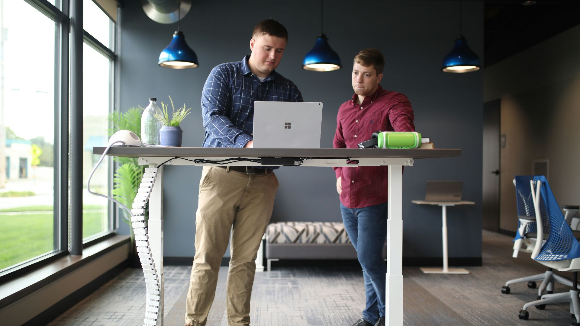 two men standing at a table with a laptop