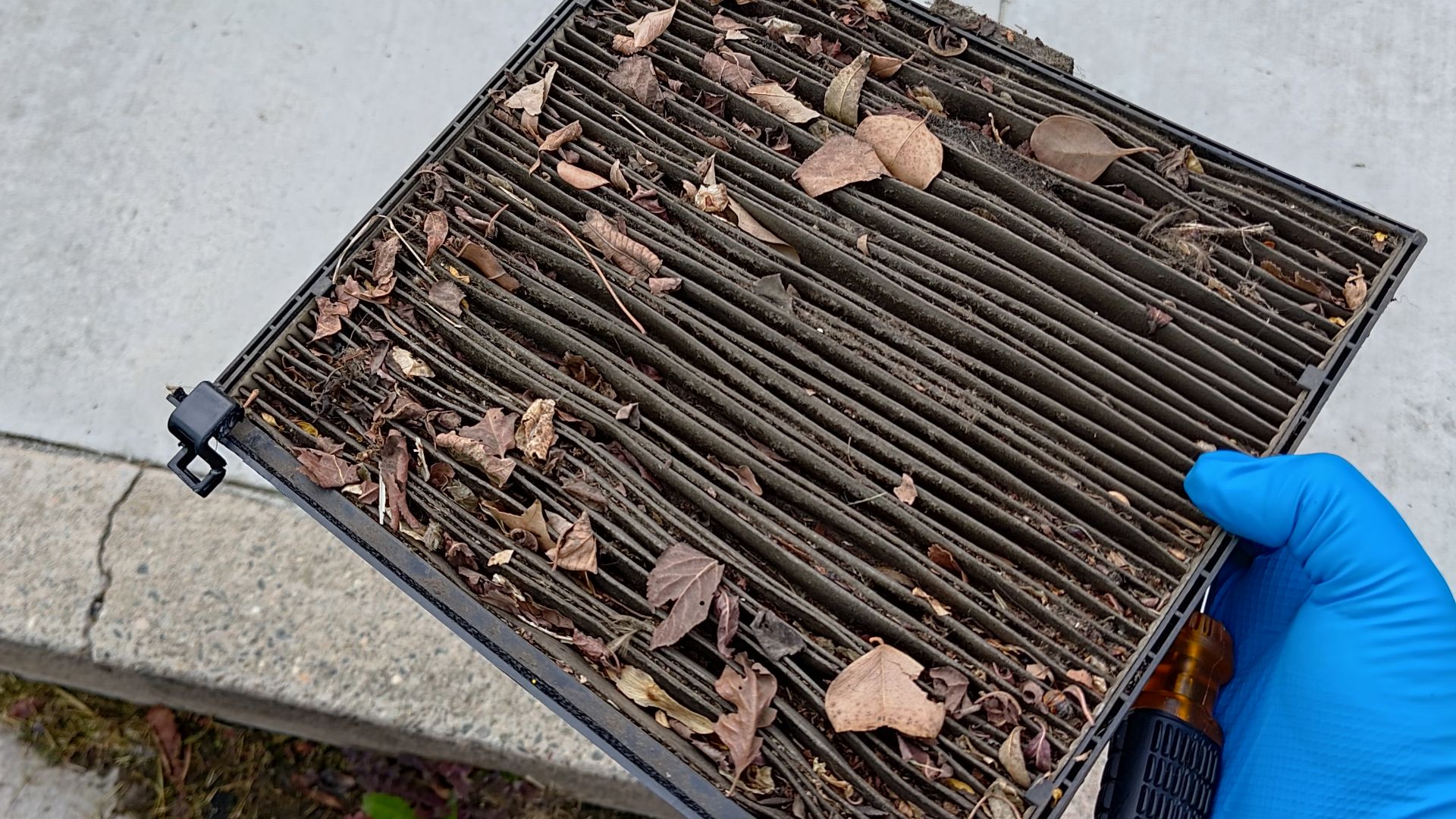 A dirty cabin filter clogged with leaves and dirt