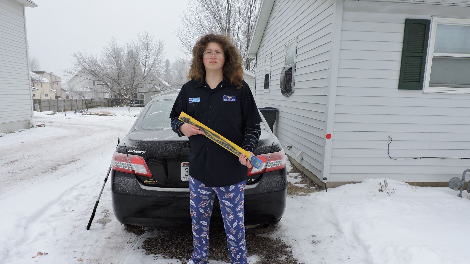 A man holding a windscreen/windshield wiper in such a way as to parody a firearm.