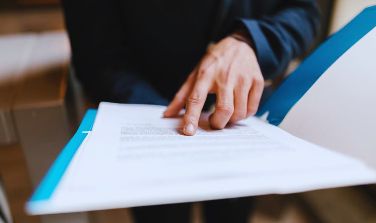 Close Up Photo of Person Pointing on White Paper