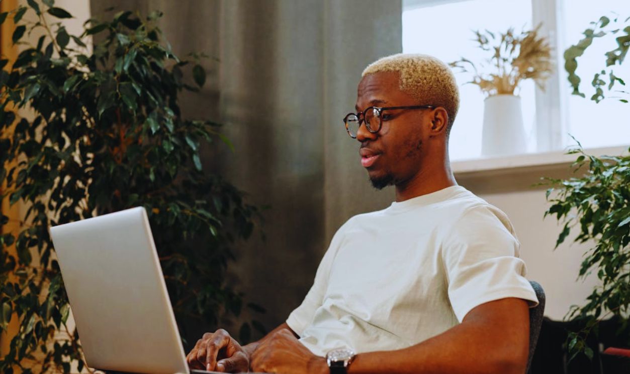 Man with Eyeglasses Using a Laptop while Sitting on a Chair