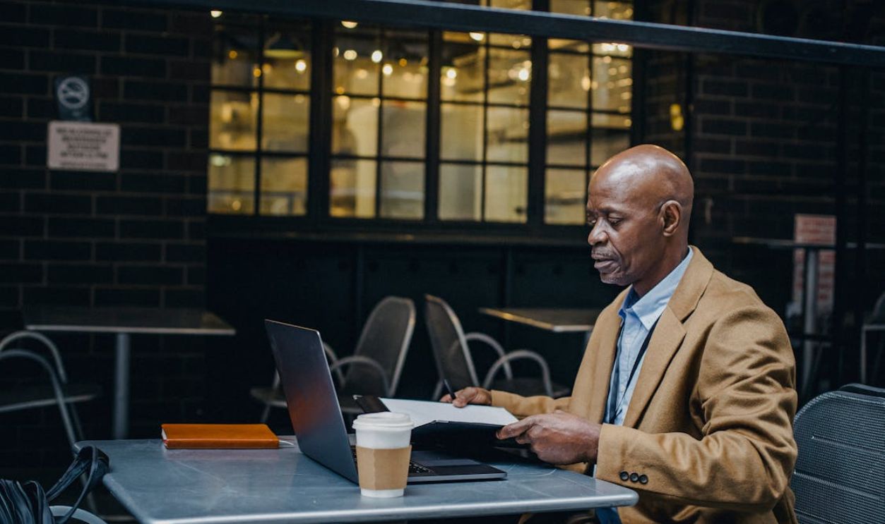 Thoughtful black man browsing laptop and opening documents in cafe