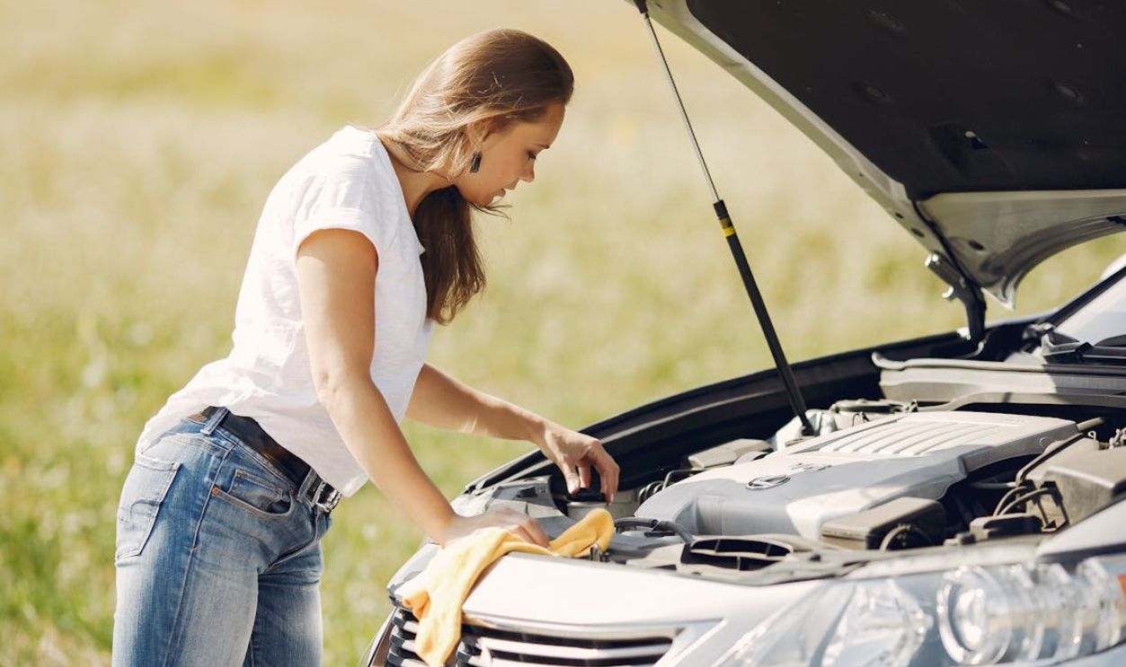 Troubled young woman near broken automobile in countryside during car accident