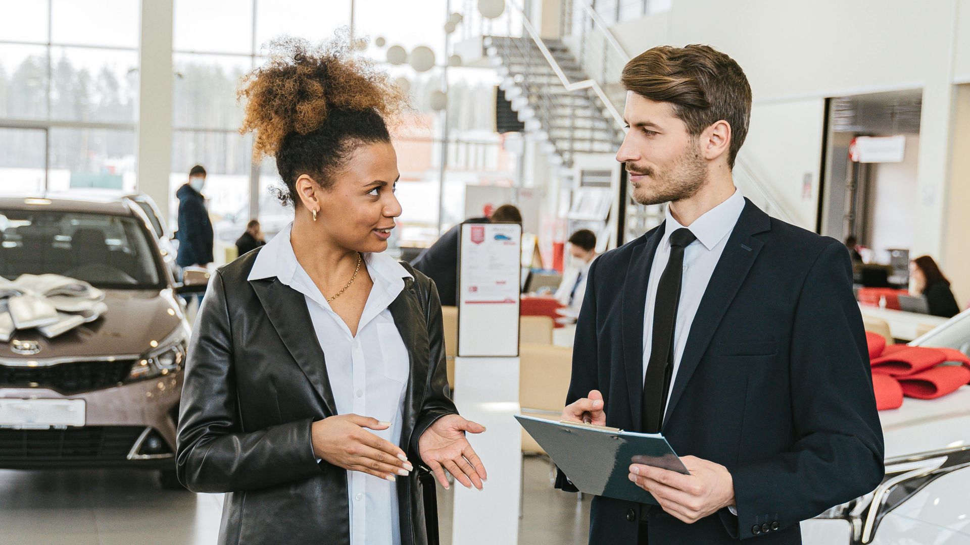 Business professionals discussing details in a car dealership showroom.