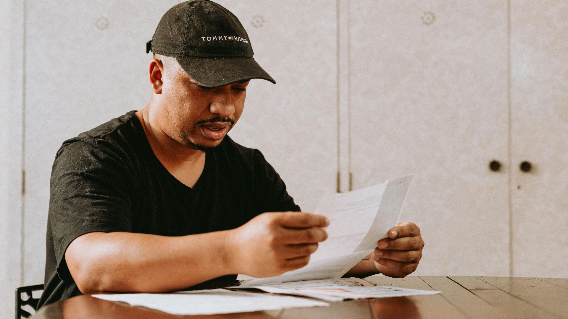 Adult man sitting at home table, focused on reviewing important documents.