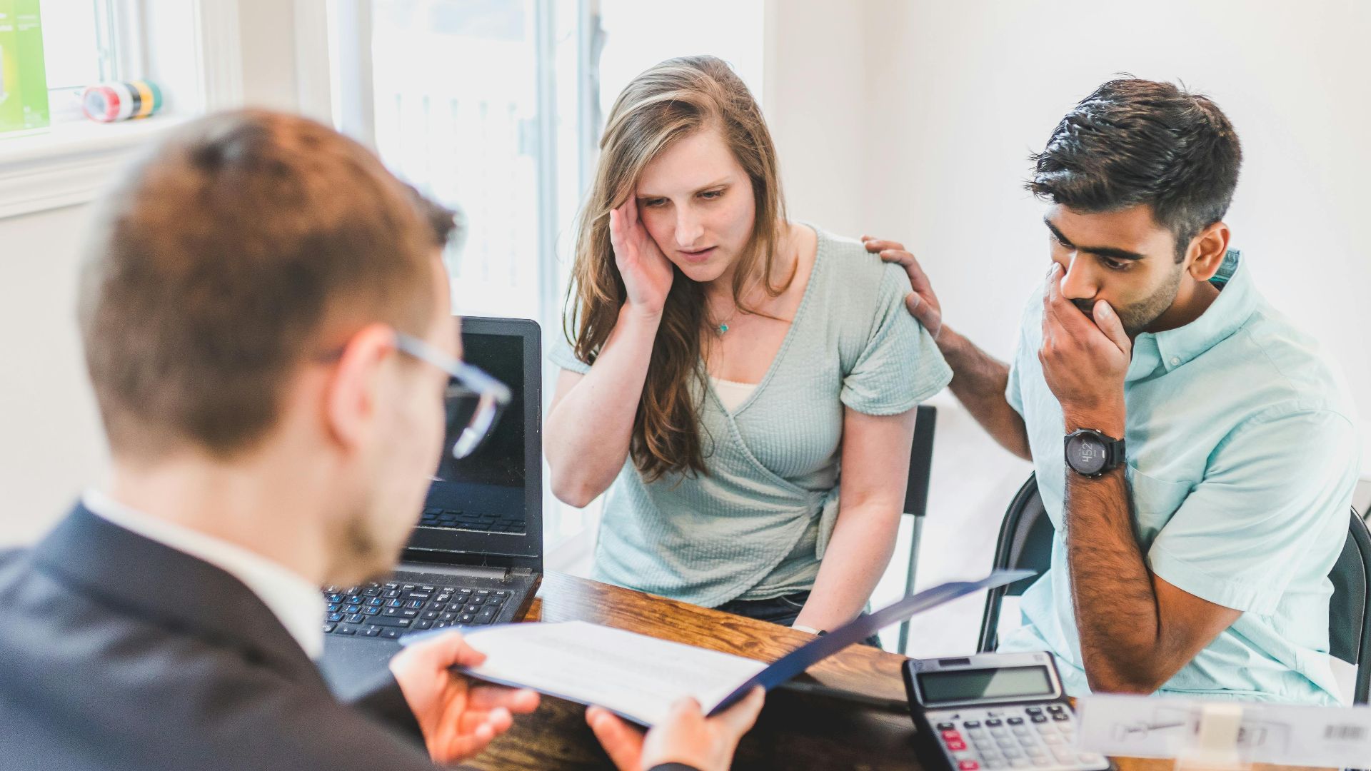 A worried couple consults with a real estate agent about home buying processes.