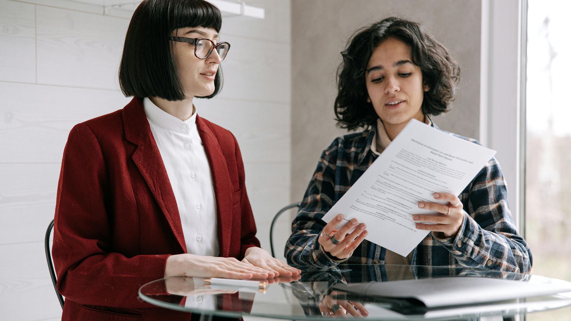 Two women reviewing real estate documents, indicating a decision or agreement indoors.