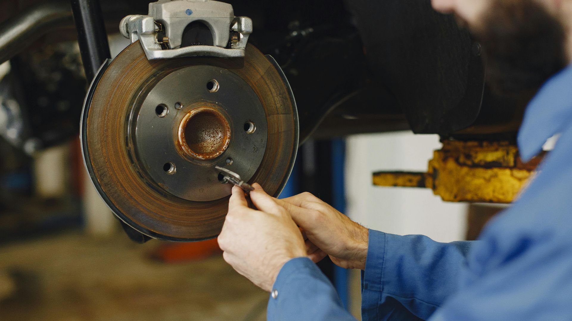 Mechanic working on brake disc in an auto repair workshop, close-up, focus on hands.