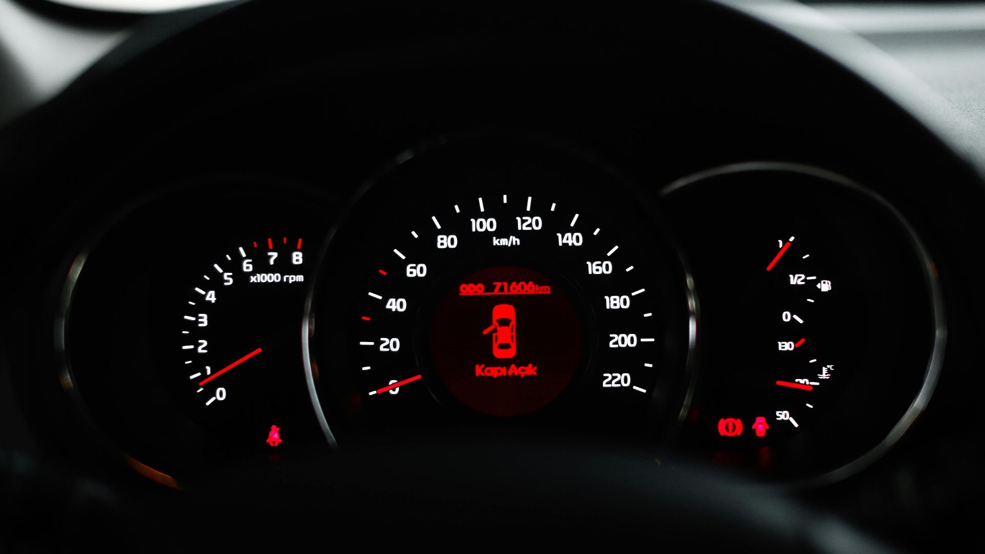 Car dashboard showing a warning light with various dials and gauges in focus.