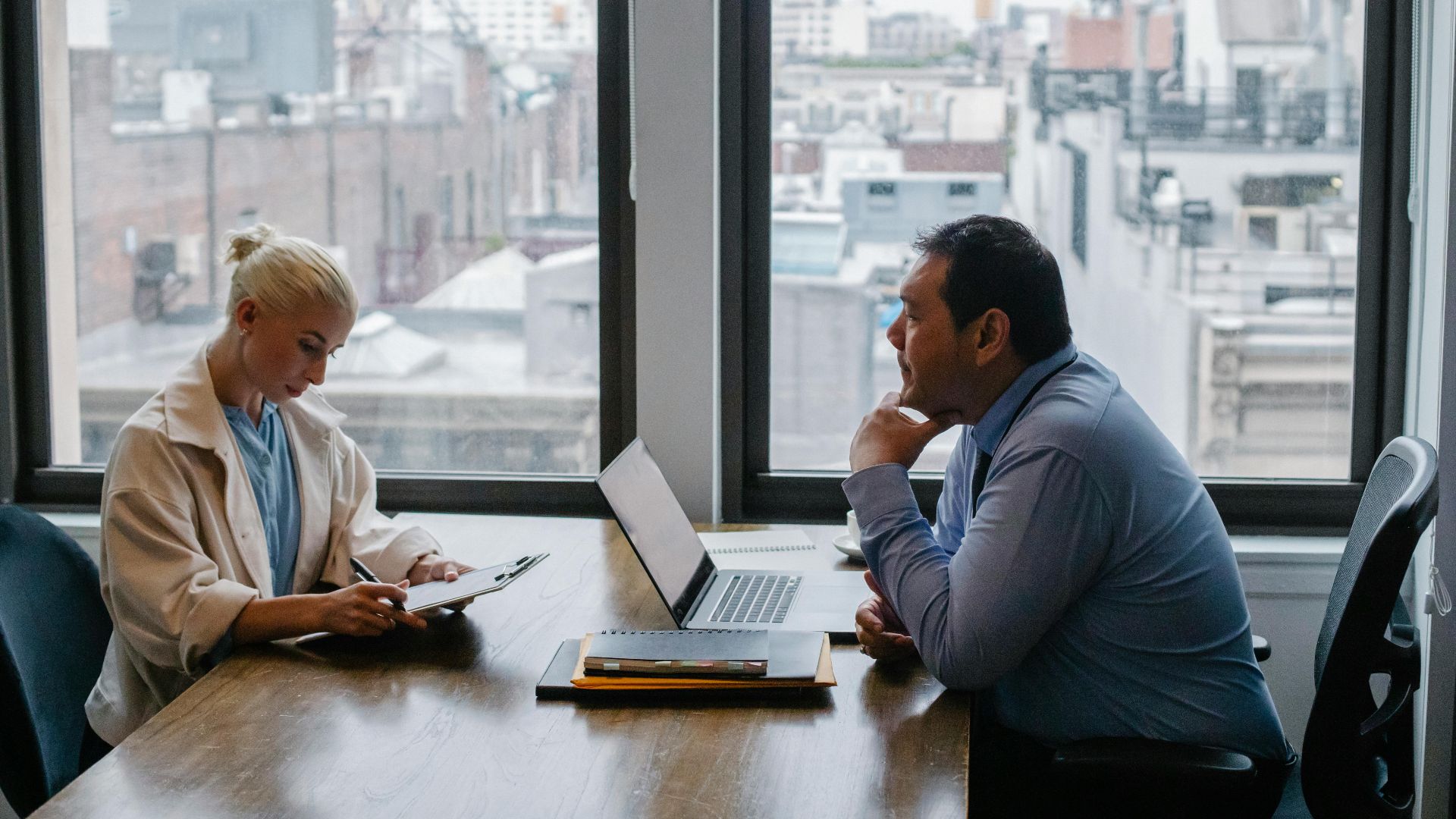 Business meeting between colleagues in a modern office setting with city view.