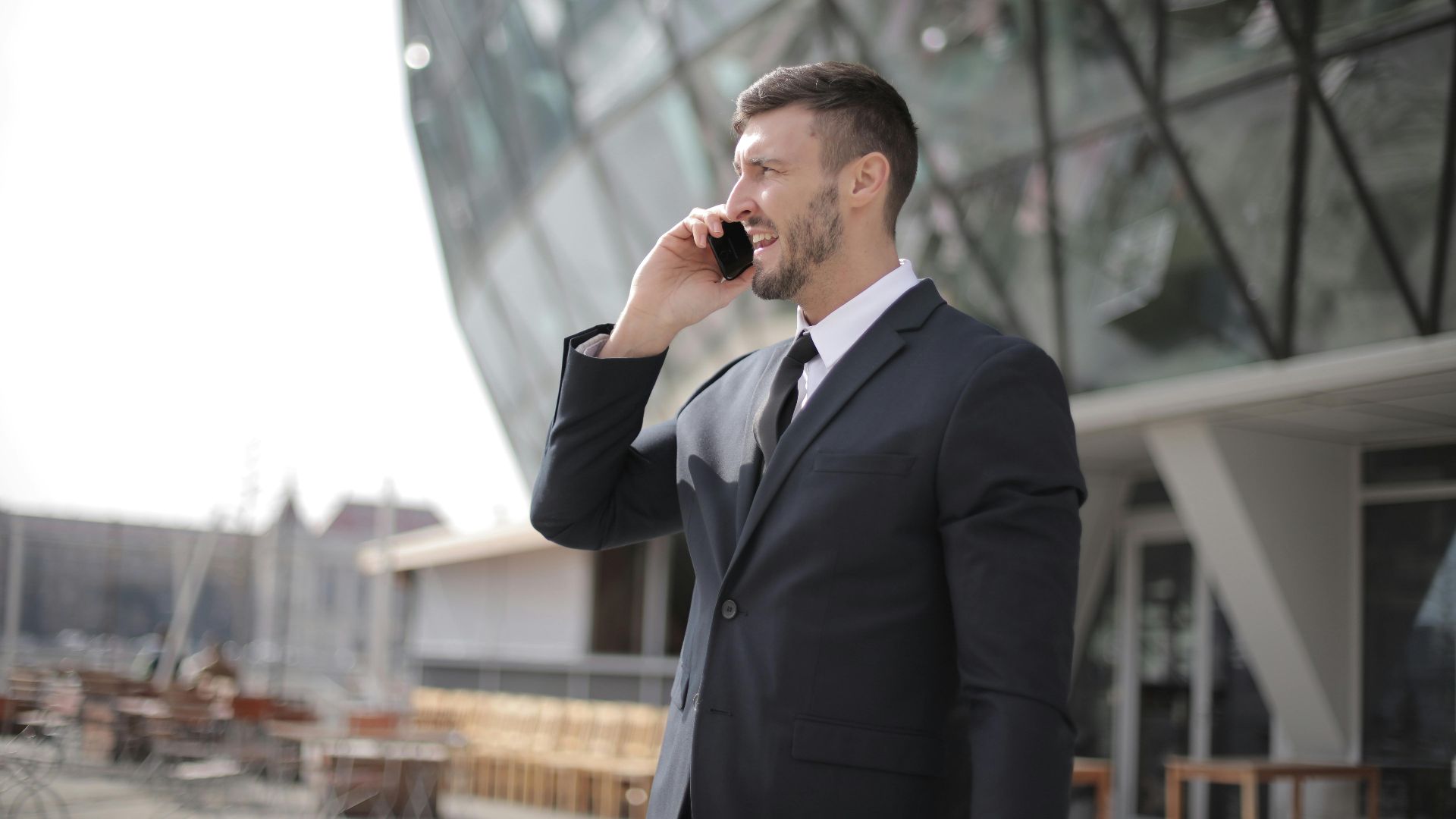 Professional man in suit using smartphone outdoors in urban corporate setting.