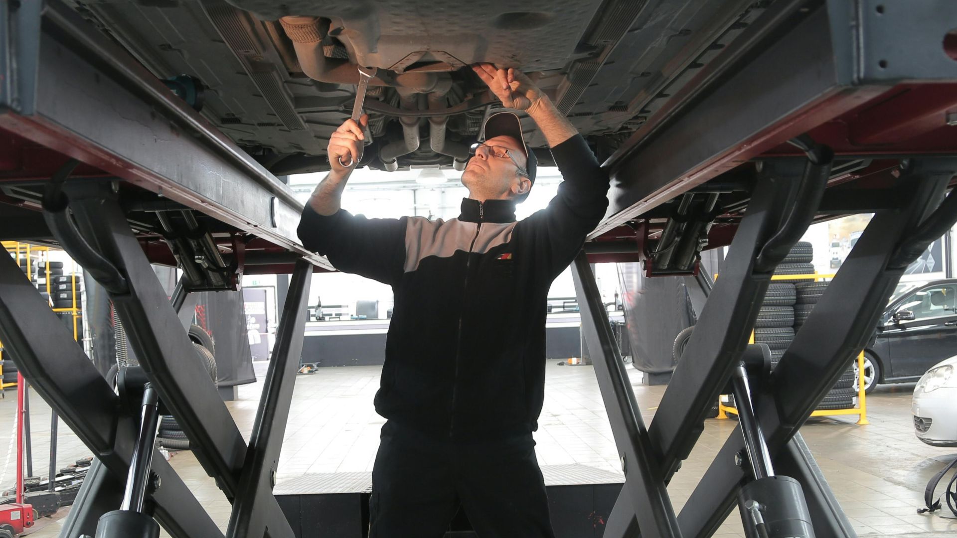Mechanic inspecting and repairing a vehicle in a professional auto garage.