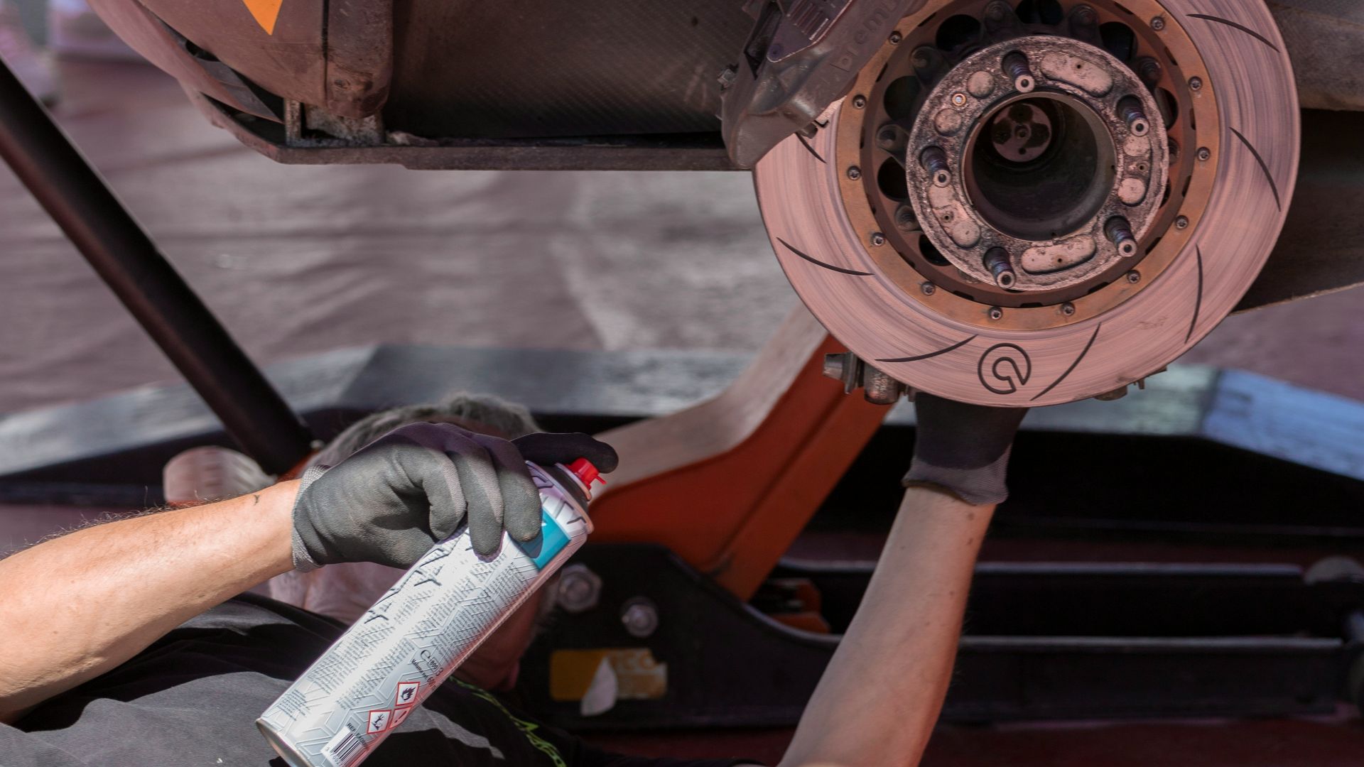 man fixing vehicle while holding spray can