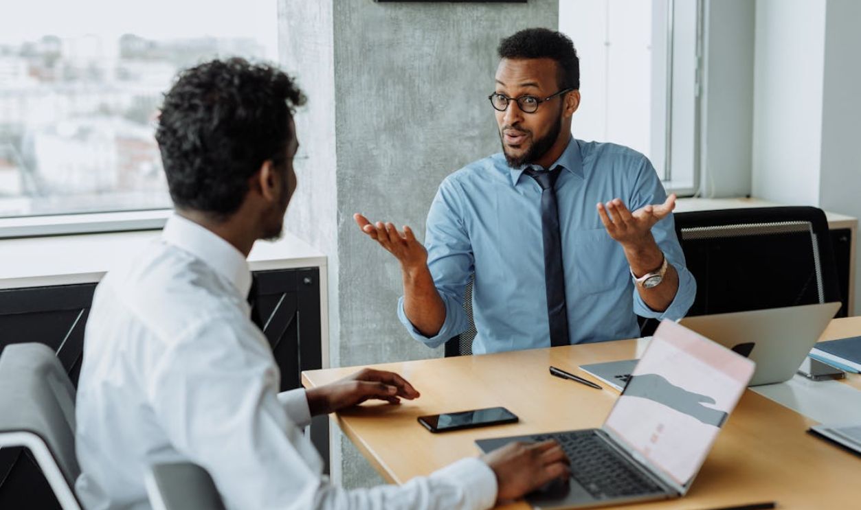Man in Blue Long Sleeve Shirt Talking to a Man in White Long Sleeve Shirt