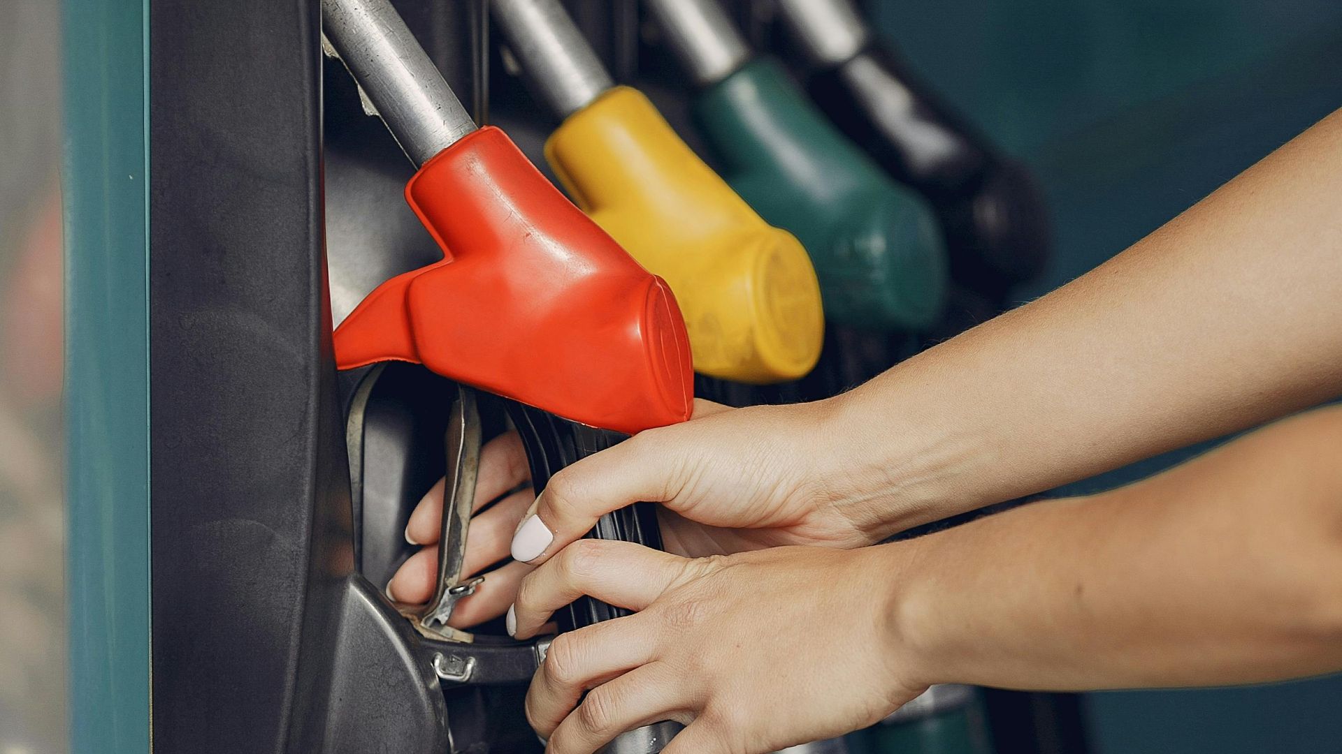 Unrecognizable female customer choosing fuel nozzle pump for filling car tank with gasoline on petrol station