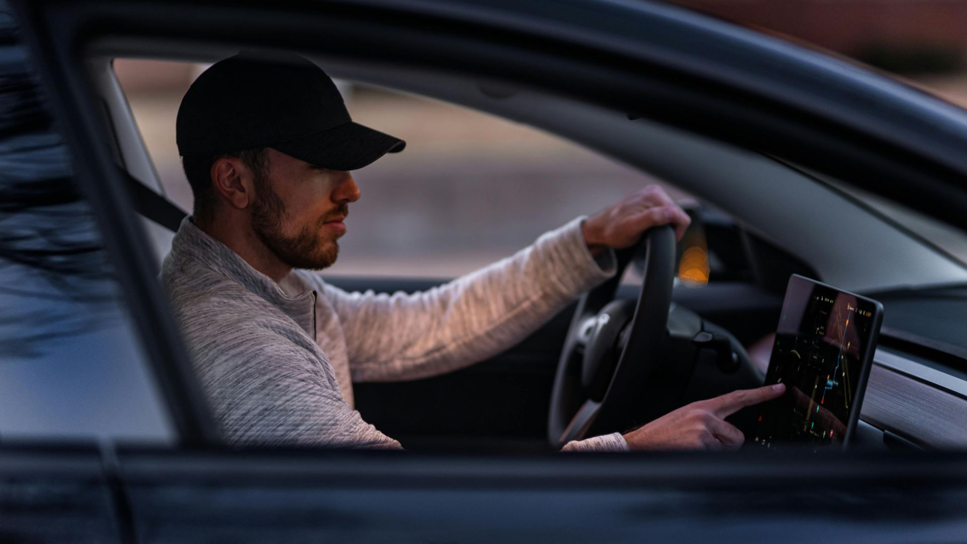 A man interacts with a touchscreen inside an electric car, driving through Dallas, TX.
