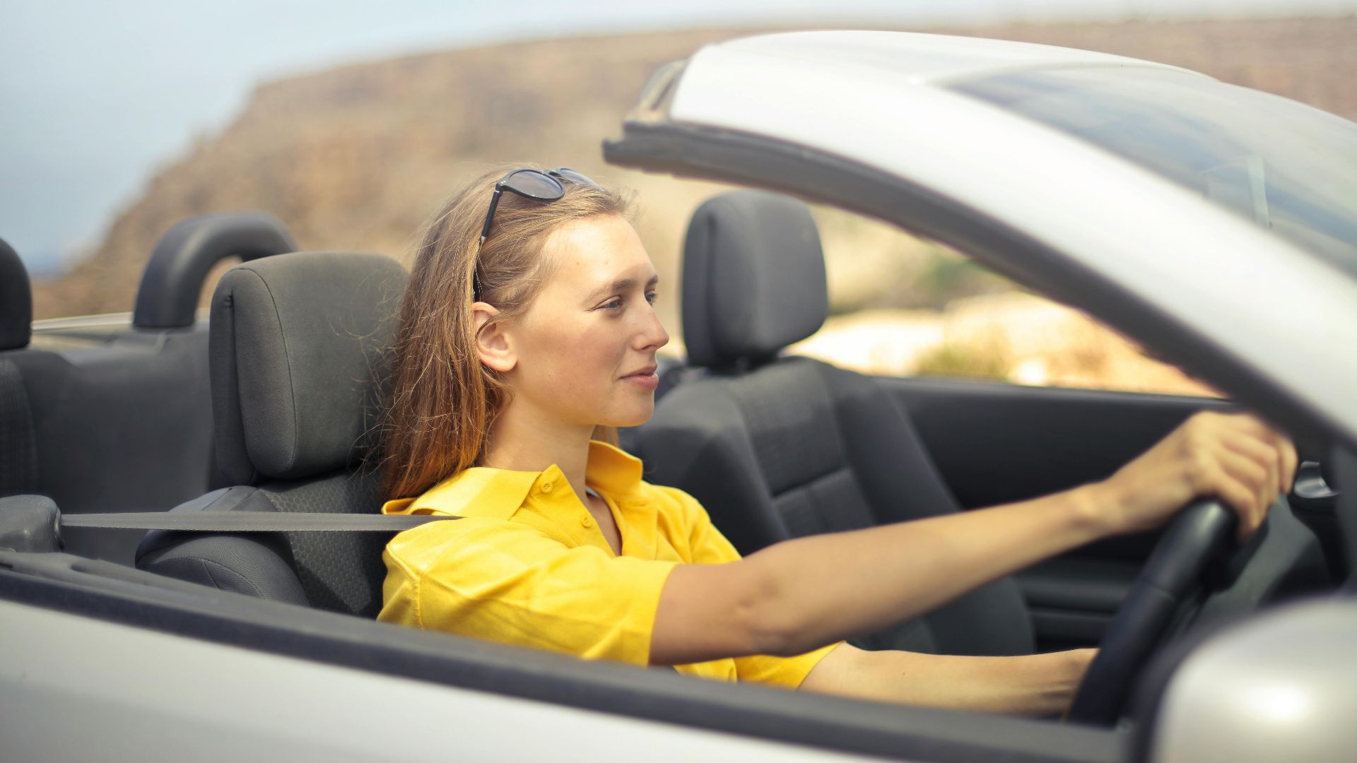 A young woman enjoys driving a convertible on a sunny day in Malta.