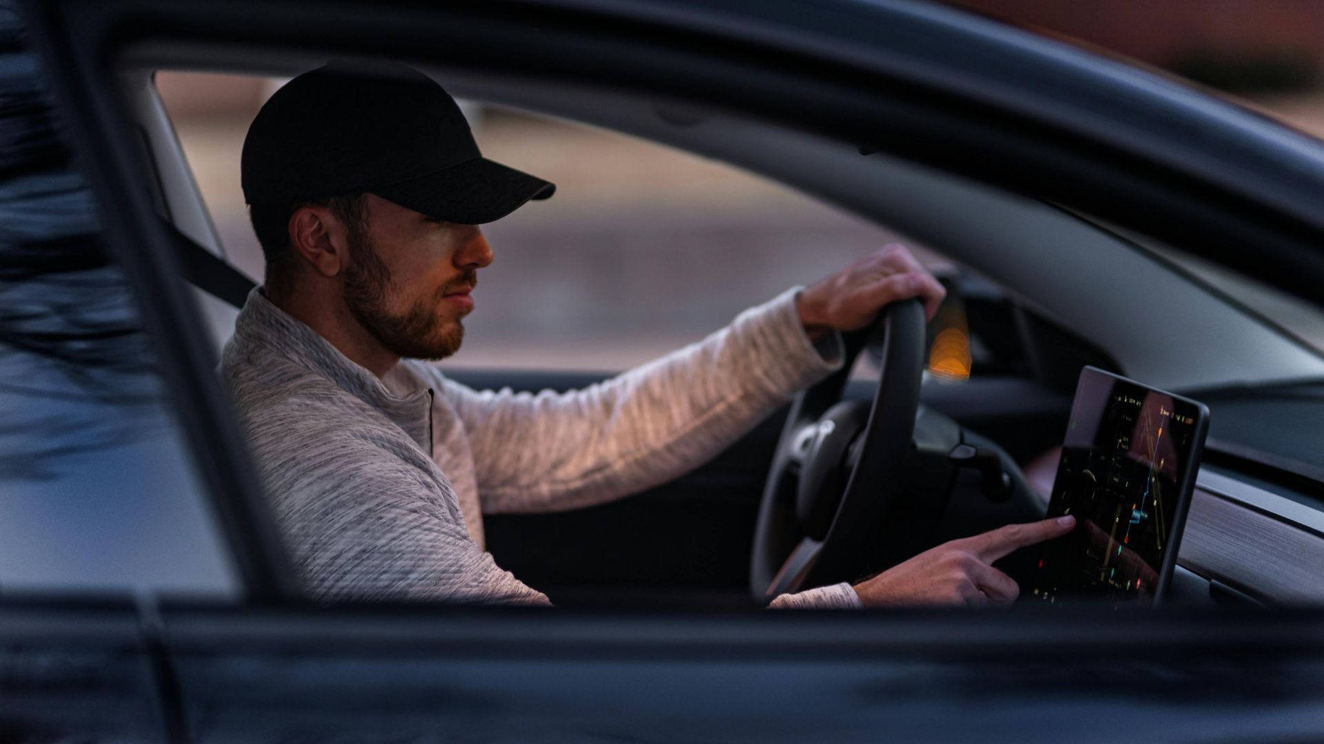A man interacts with a touchscreen inside an electric car, driving through Dallas, TX.