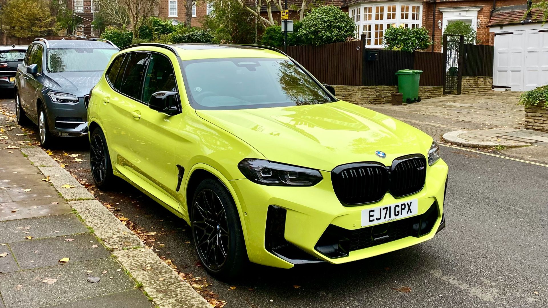 a yellow bmw suv parked on the side of the road
