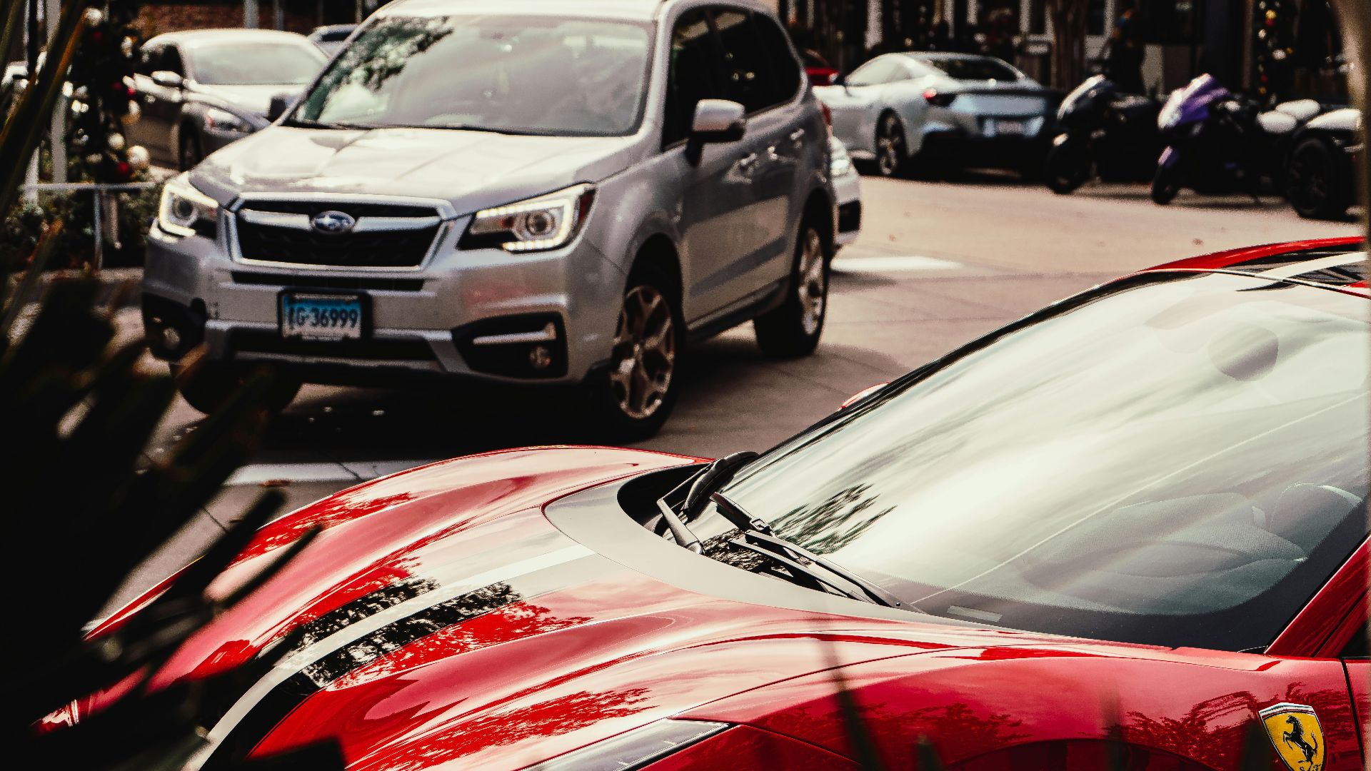 A striking red luxury sports car parked on a city street alongside other vehicles.