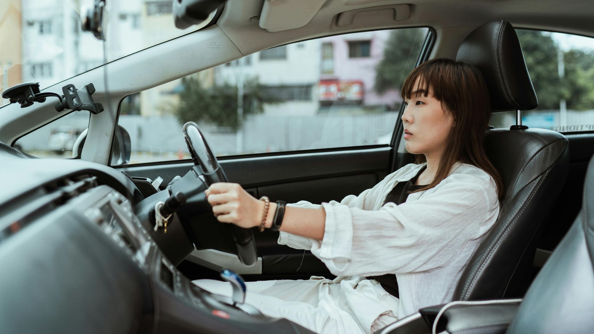 Confident young woman driving in the city, focused and pensive.